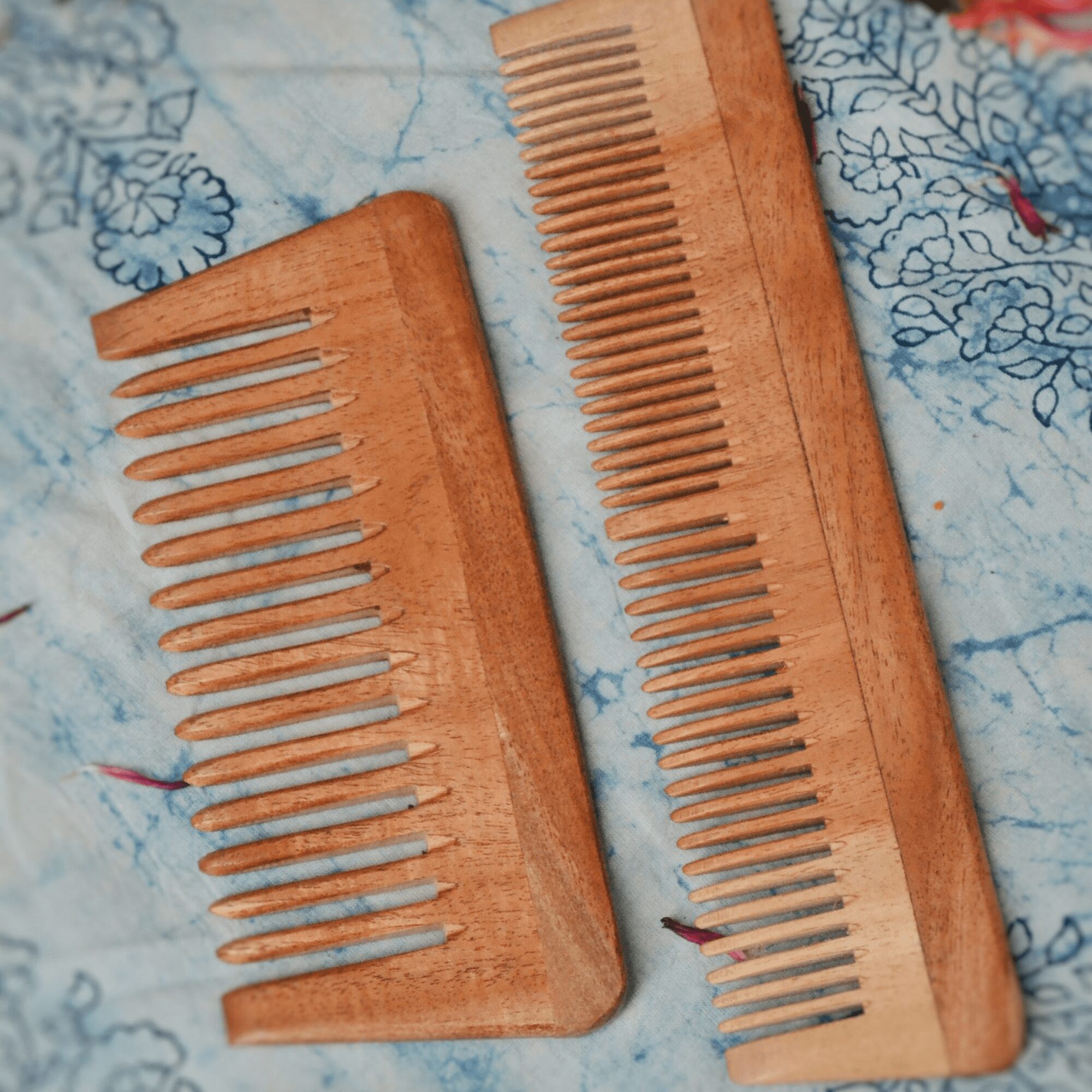 “Handcrafted neem wood wide-tooth comb on rustic surface with berries and flowers – eco-friendly detangle
