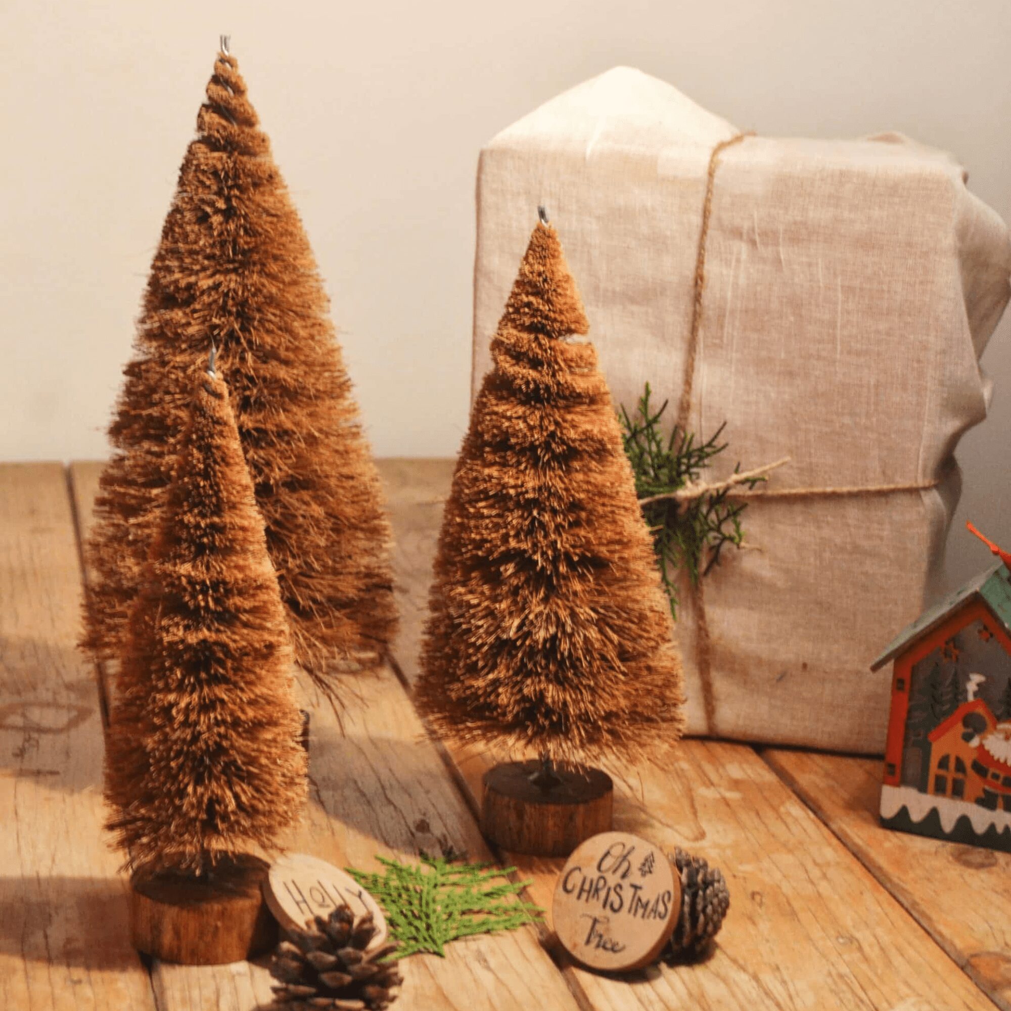 A handcrafted Christmas tree made from natural coconut coir fiber and mounted on a rustic wooden base, surrounded by pinecones and eco-friendly holiday decor — sustainable Christmas decoration by Almitra Sustainables.