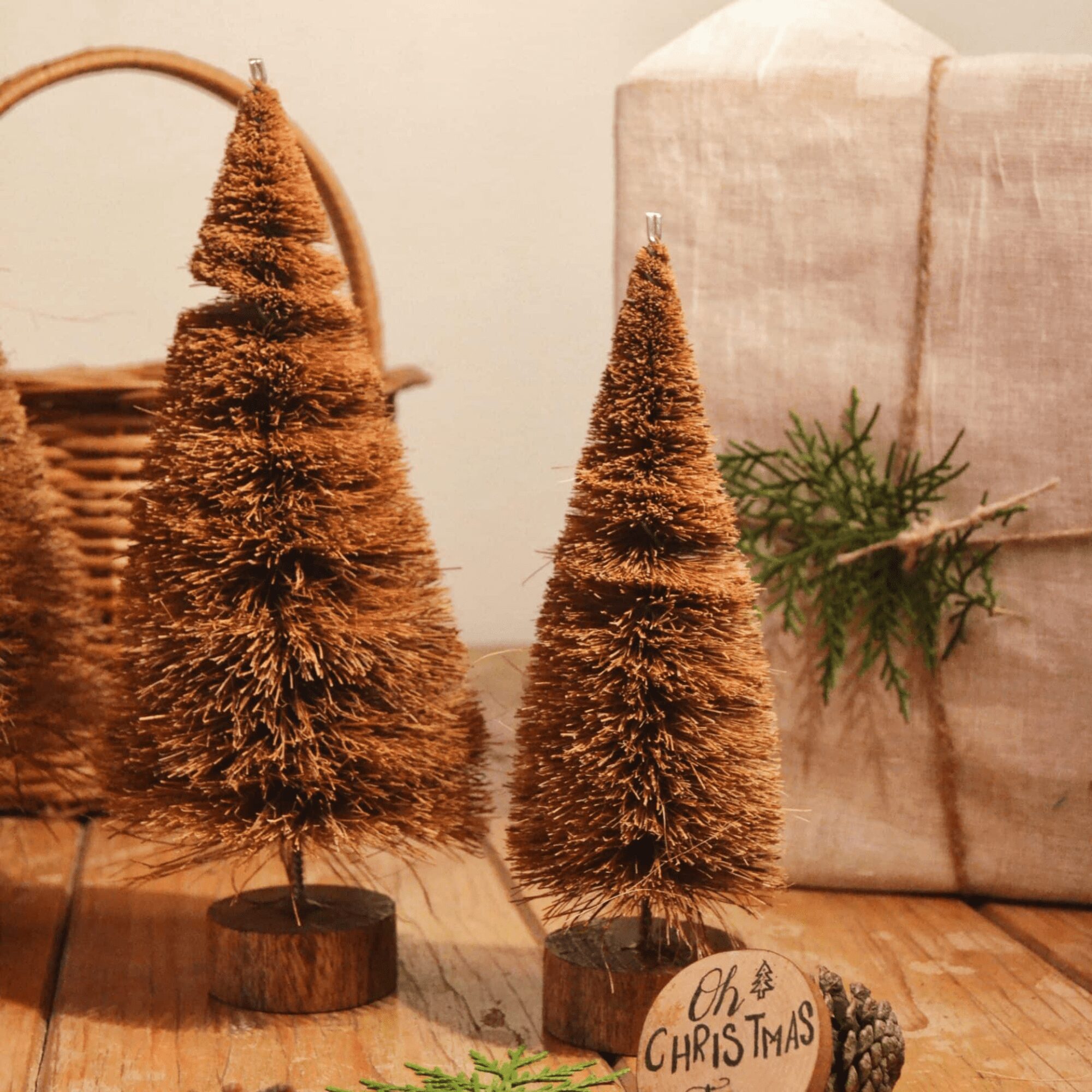 A 38 cm handcrafted Christmas tree made from natural coconut coir fiber and mounted on a rustic wooden base, surrounded by pinecones and eco-friendly holiday decor — sustainable Christmas decoration by Almitra Sustainables.