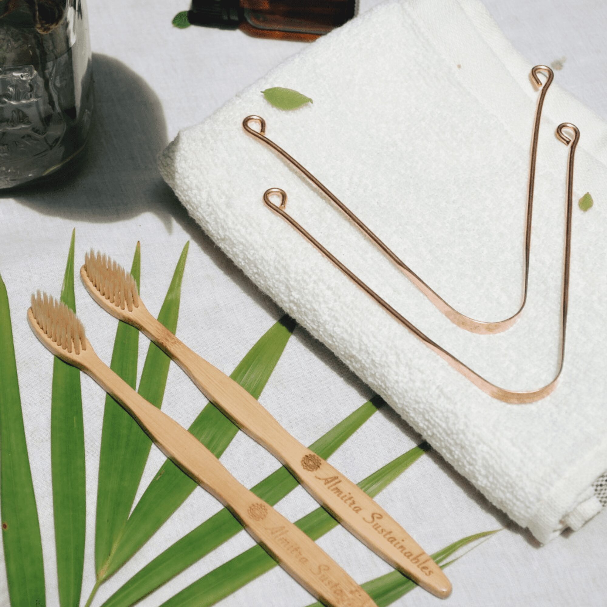 Flat lay of eco-friendly bamboo toothbrushes with soft plant-based bristles and copper tongue cleaners on a towel, ideal for sustainable oral care.